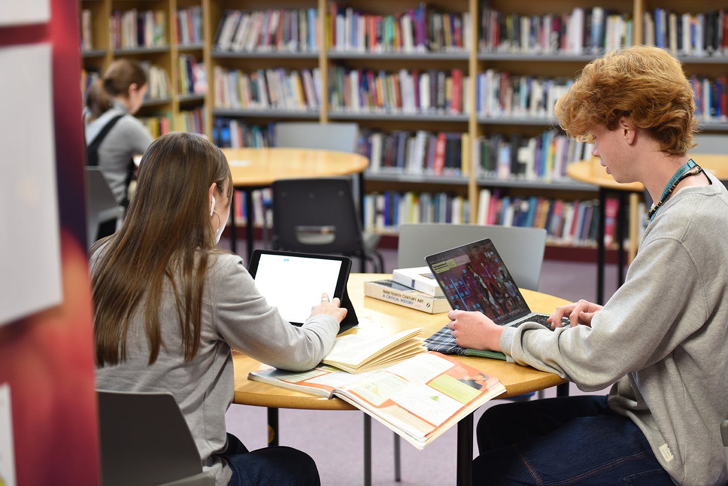 Two students working on their tablets in the library