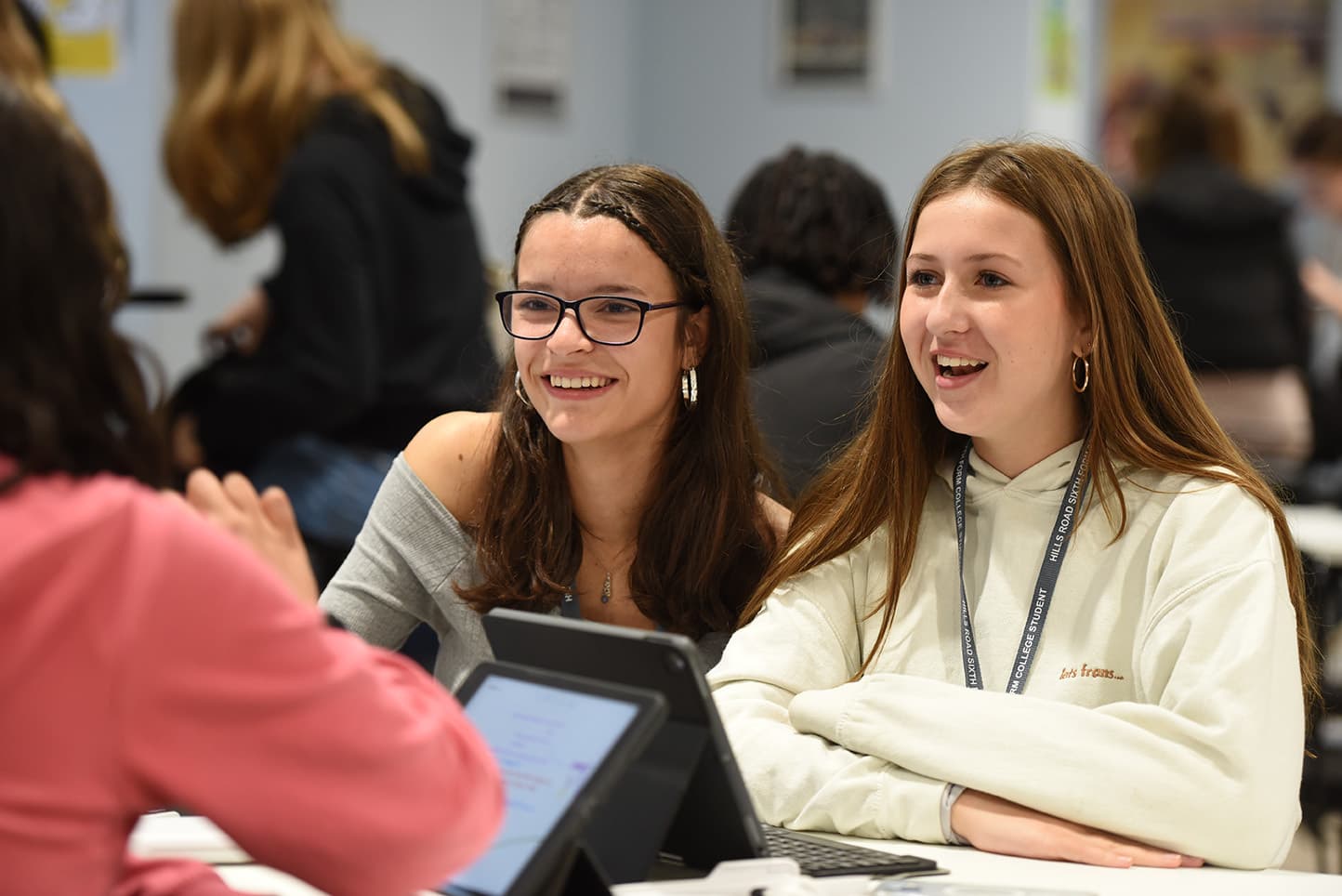 Two students sitting together talking with another students