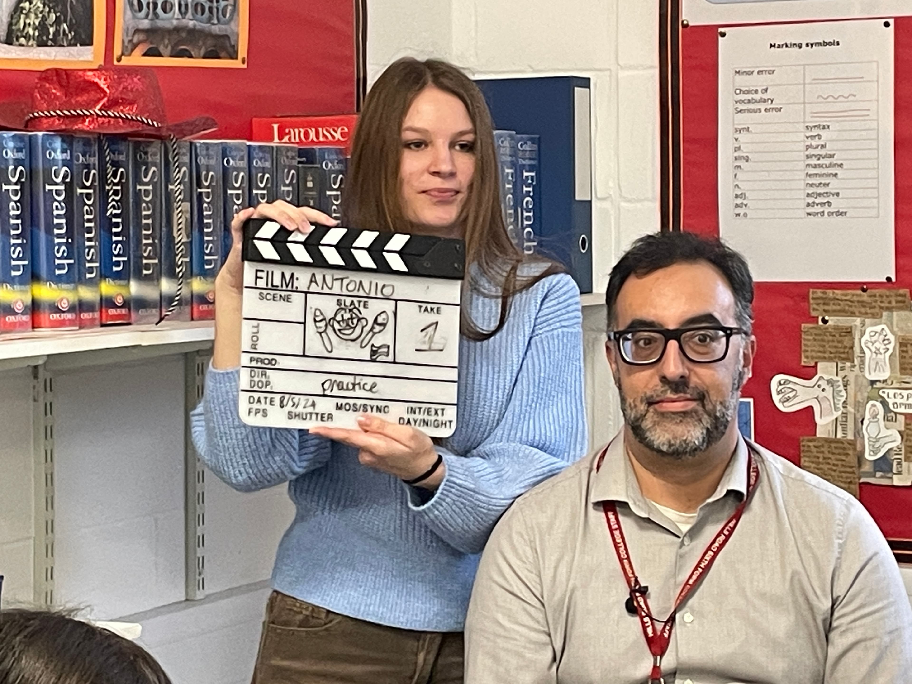 Student with clapperboard behind the scenes