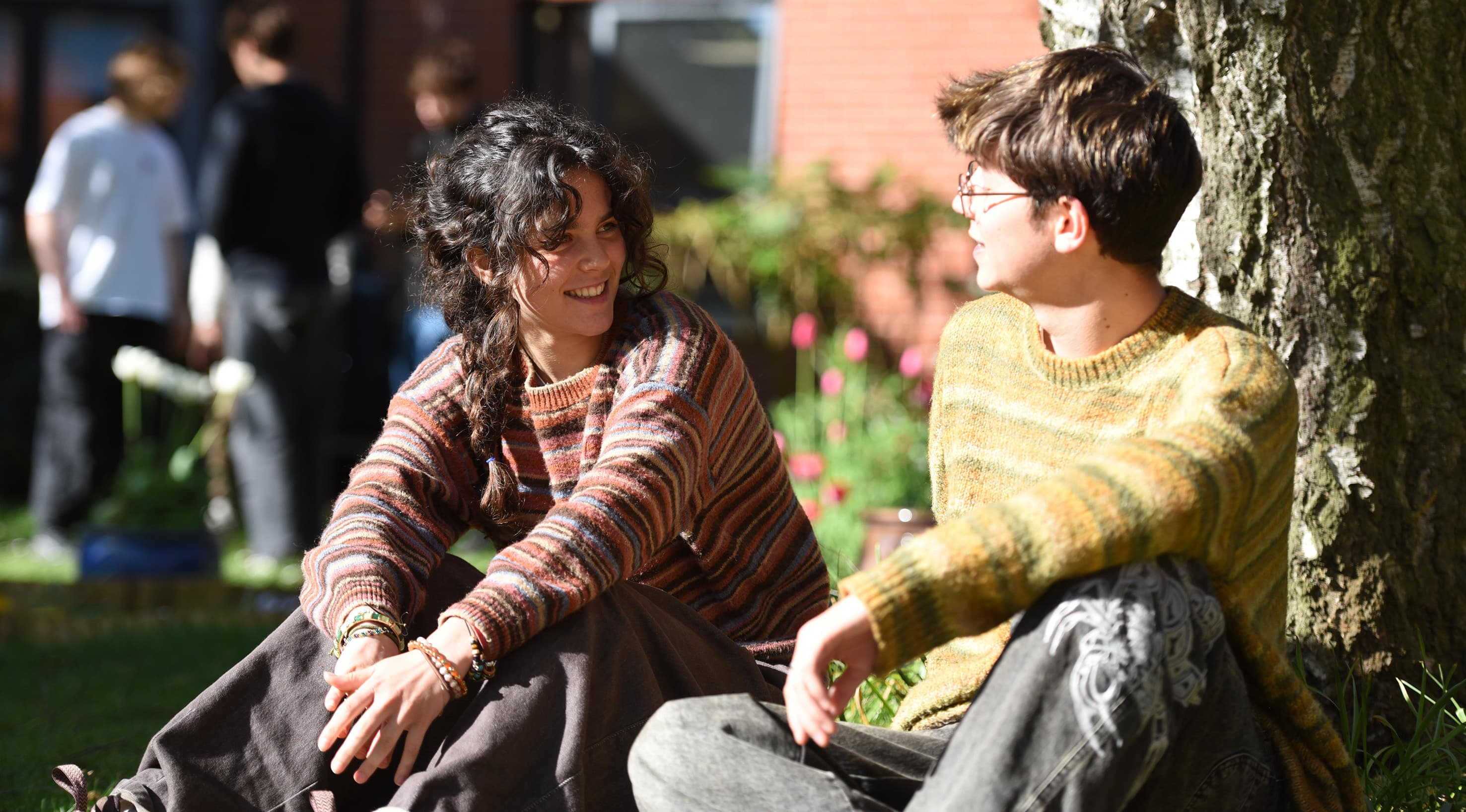 Two students sitting under a tree