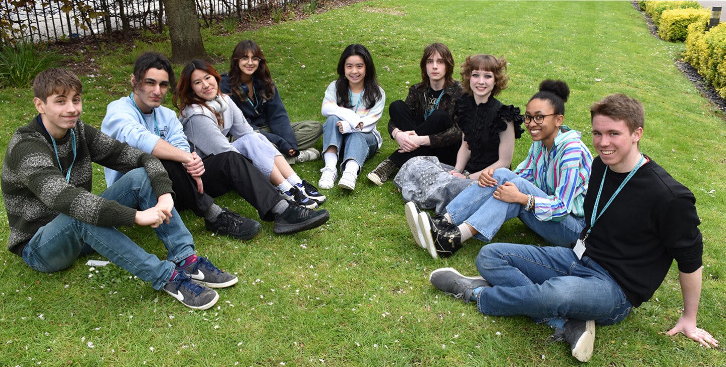 nine students sitting on grass